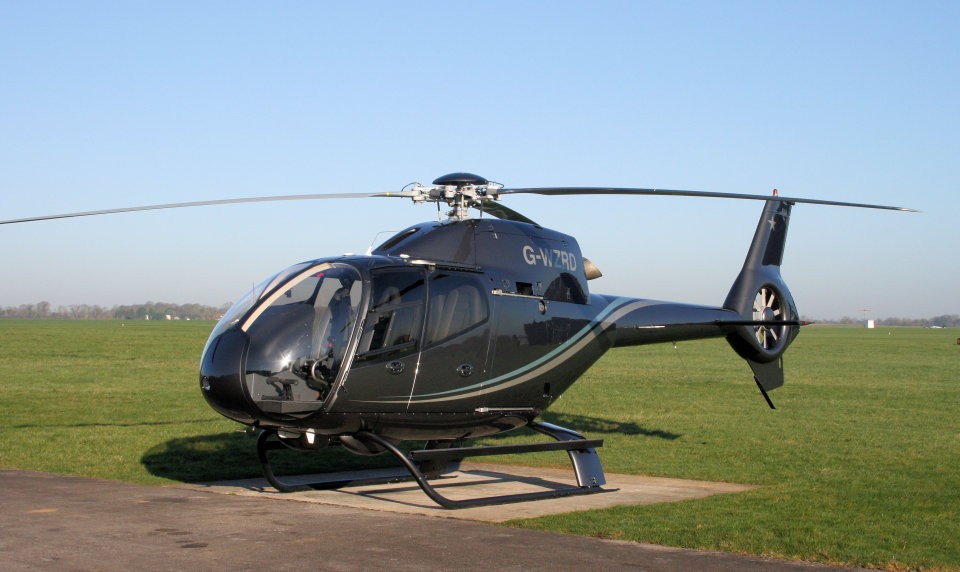 An image of a white single-bladed private helicopter landing