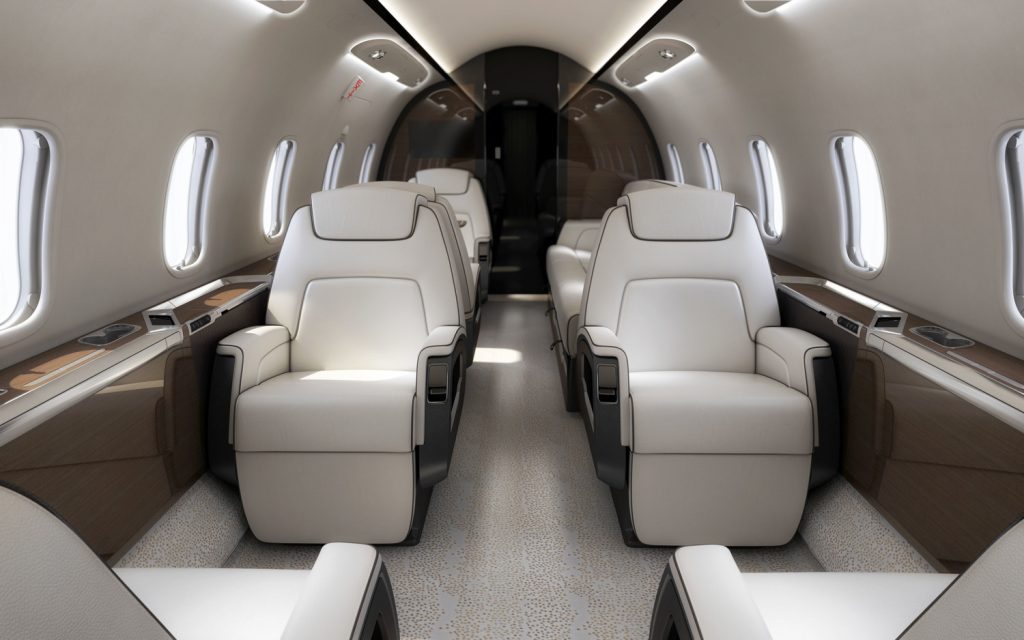 An interior shot of a private jet, It appears as white and crisp and has seats lining each side of the jet.
